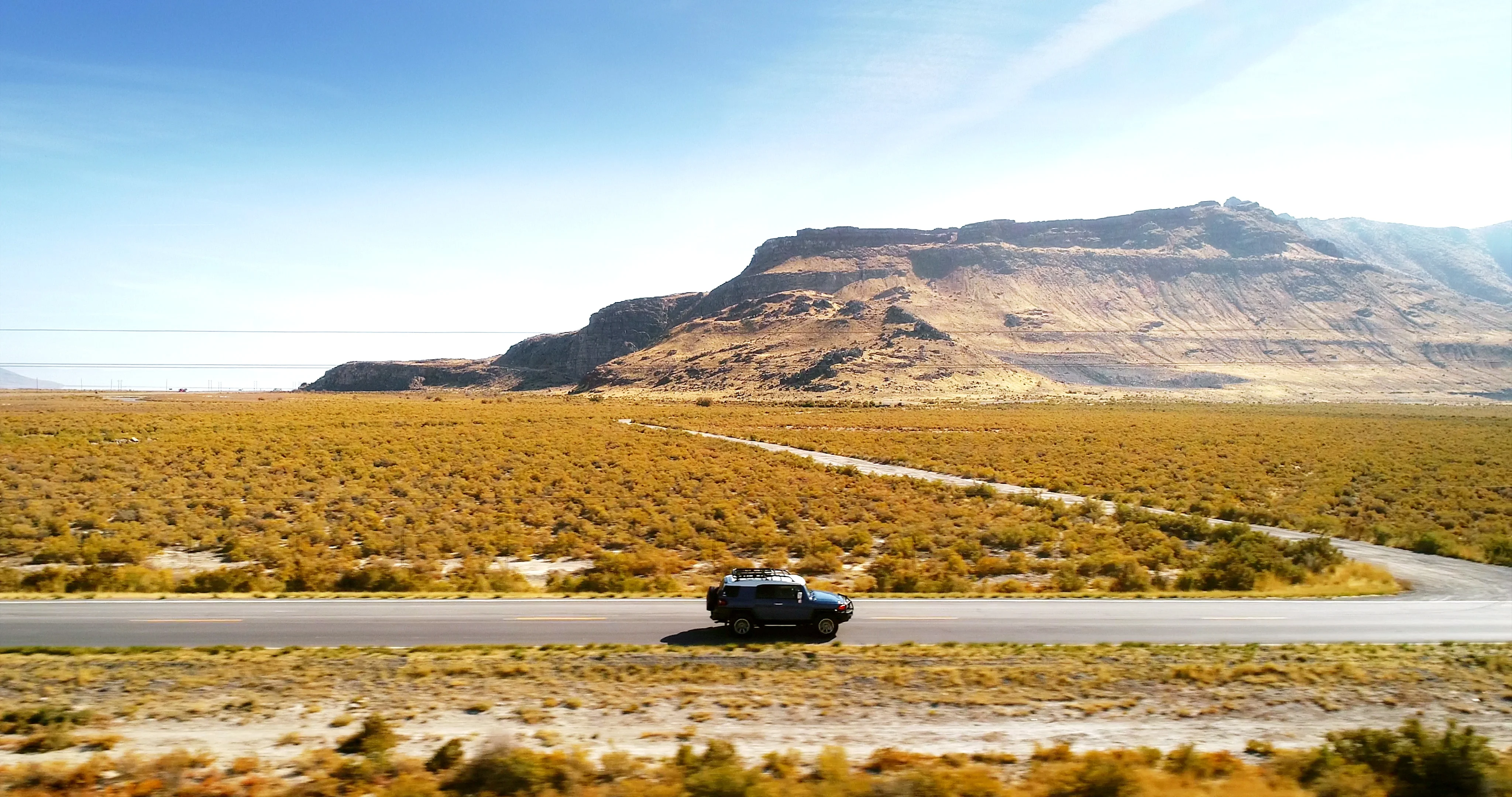 SUV on desert highway with mesa